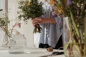 Florist arranging a vibrant spring bouquet with various flowers in a sunlit room.