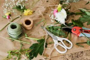 Top view of floral arrangement tools and materials on a wooden workbench.